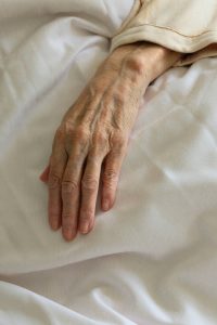 Hand van overledene in bed in Hospice. Wat te doen na overlijden in Hospice?